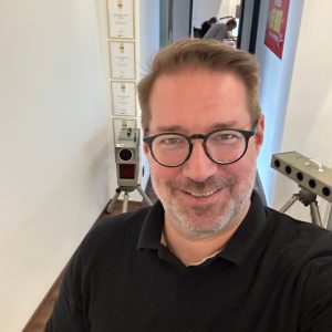 Tim Geissler macht ein Selfie zwischen zwei Blitzgeräten